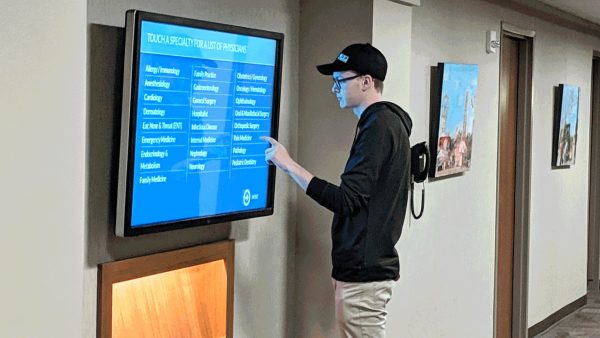 Patient using hospital digital signage to find a doctors location in the healthcare building