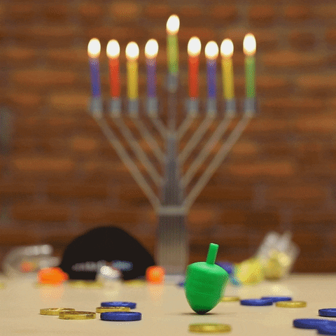 Happy Hanukkah This is a animated graphic with a with spinning green menorah. Theres a colorful menorah, in the background and gold and blue coins laying on a table.