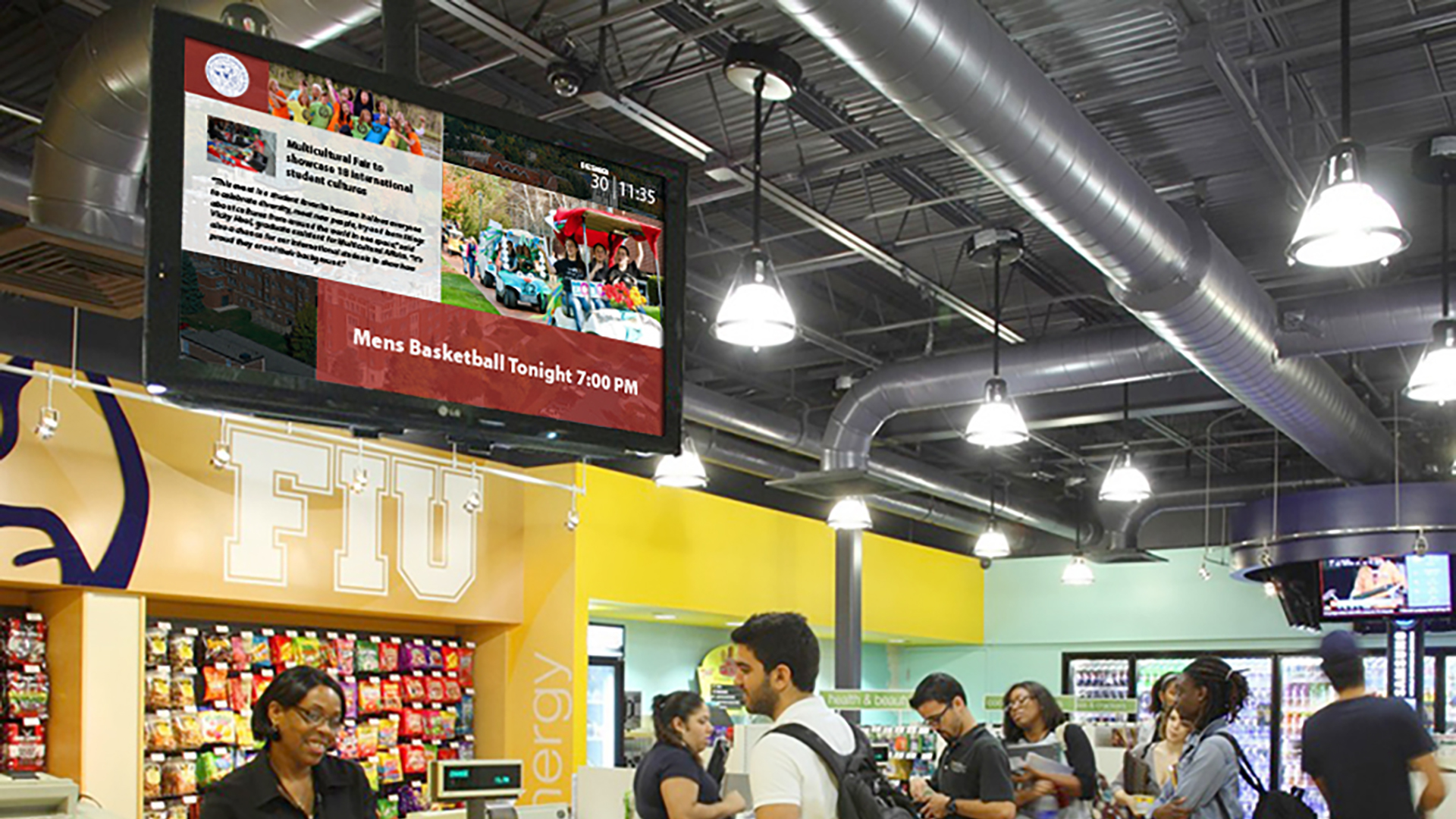 A college digital signage screens hangs from the ceiling playing school content and news for students to see while they wait to check out of a bookstore