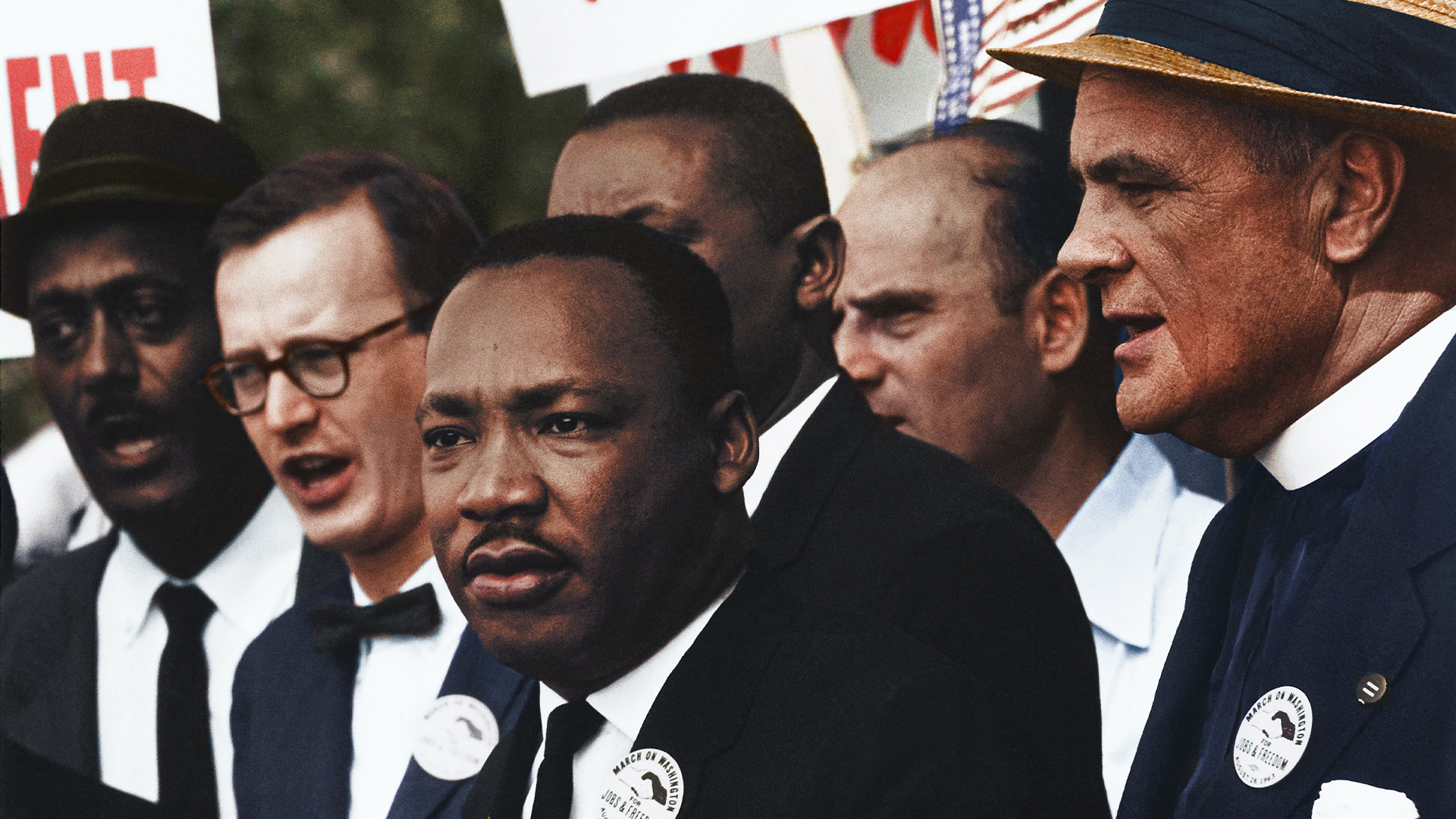 A photo of Martin Luther King Jr. looking out to the distance. He is surrounded by 5 other men who are standing behind him.