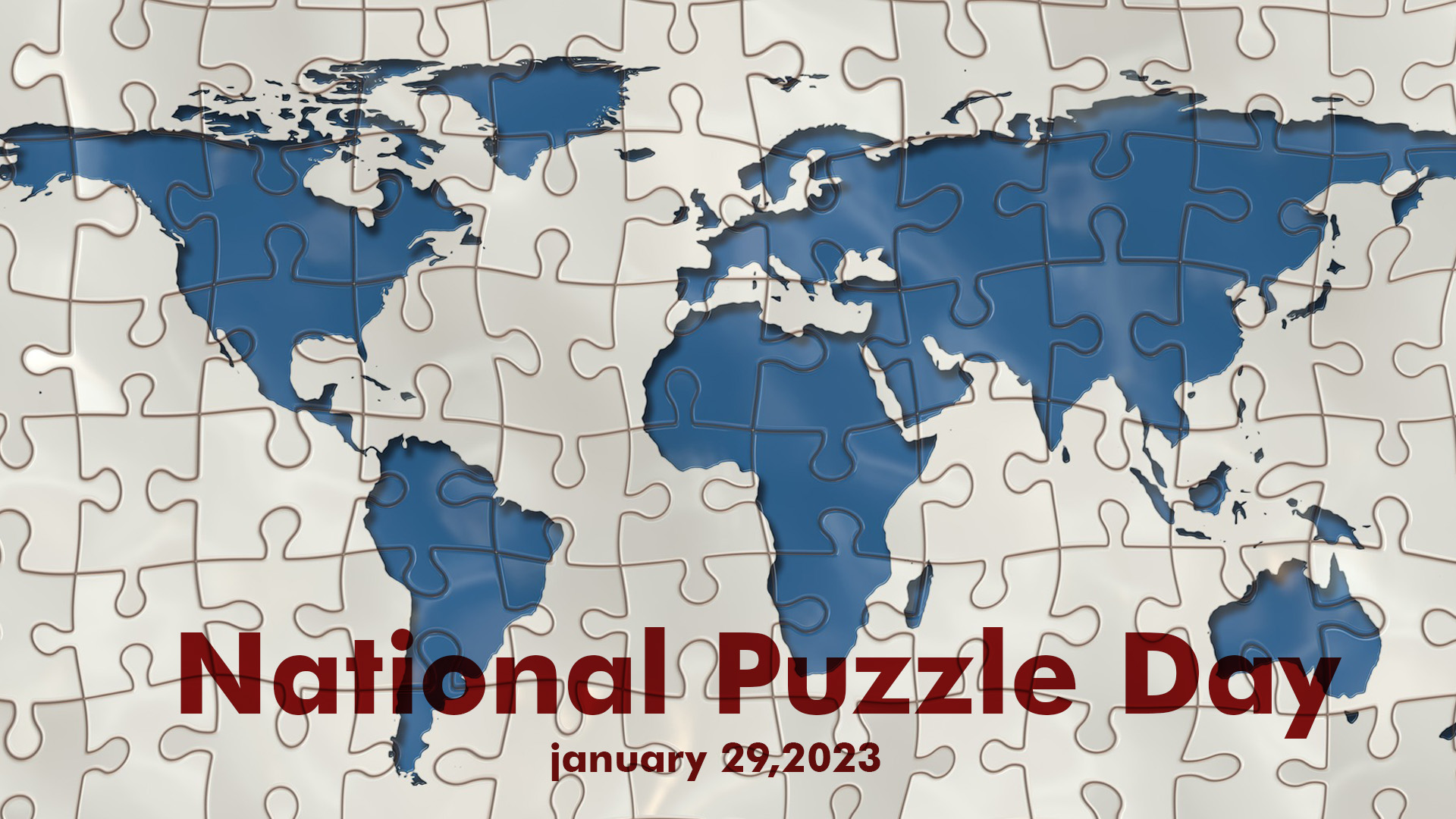 There is a animated puzzle of the world. The background id white and the countries are blue. National Puzzle Day January 29, 2023 is read across the bottom middle of the graphic in a deep red font.