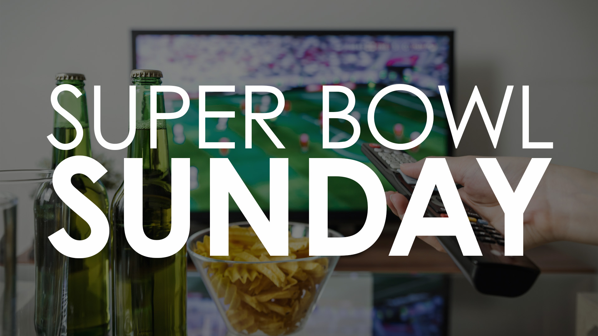 White "Super Bowl Sunday" spanned across the screen with a photo in the background of two glasses, a bowl of chips, a remote in hand, and the tv displaying some football.