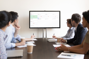 people in a conference room looking at an AppSheet app on a large monitor