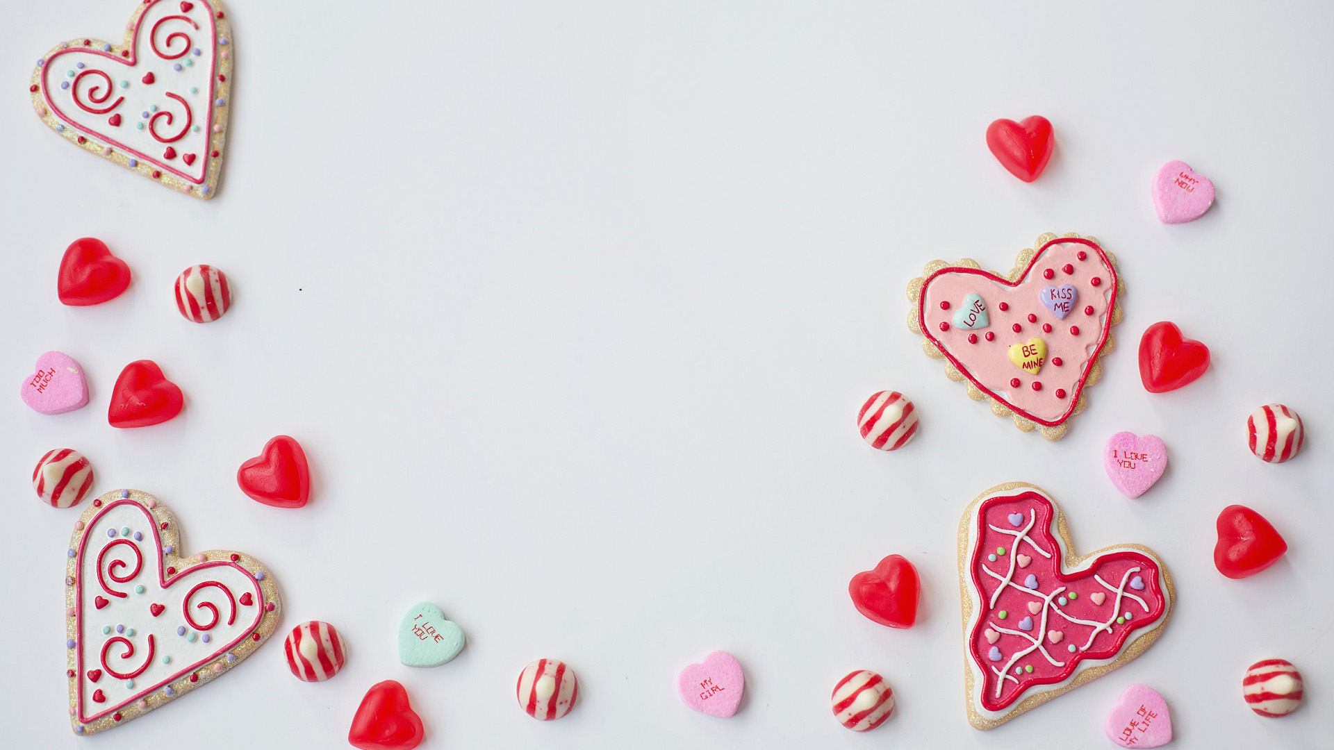 White background with frosted heart shaped cookies. Other candies like red and white kisses, red hard candy hearts, and sugar message hearts, are dispersed across the bottom and left and right side of the graphic.