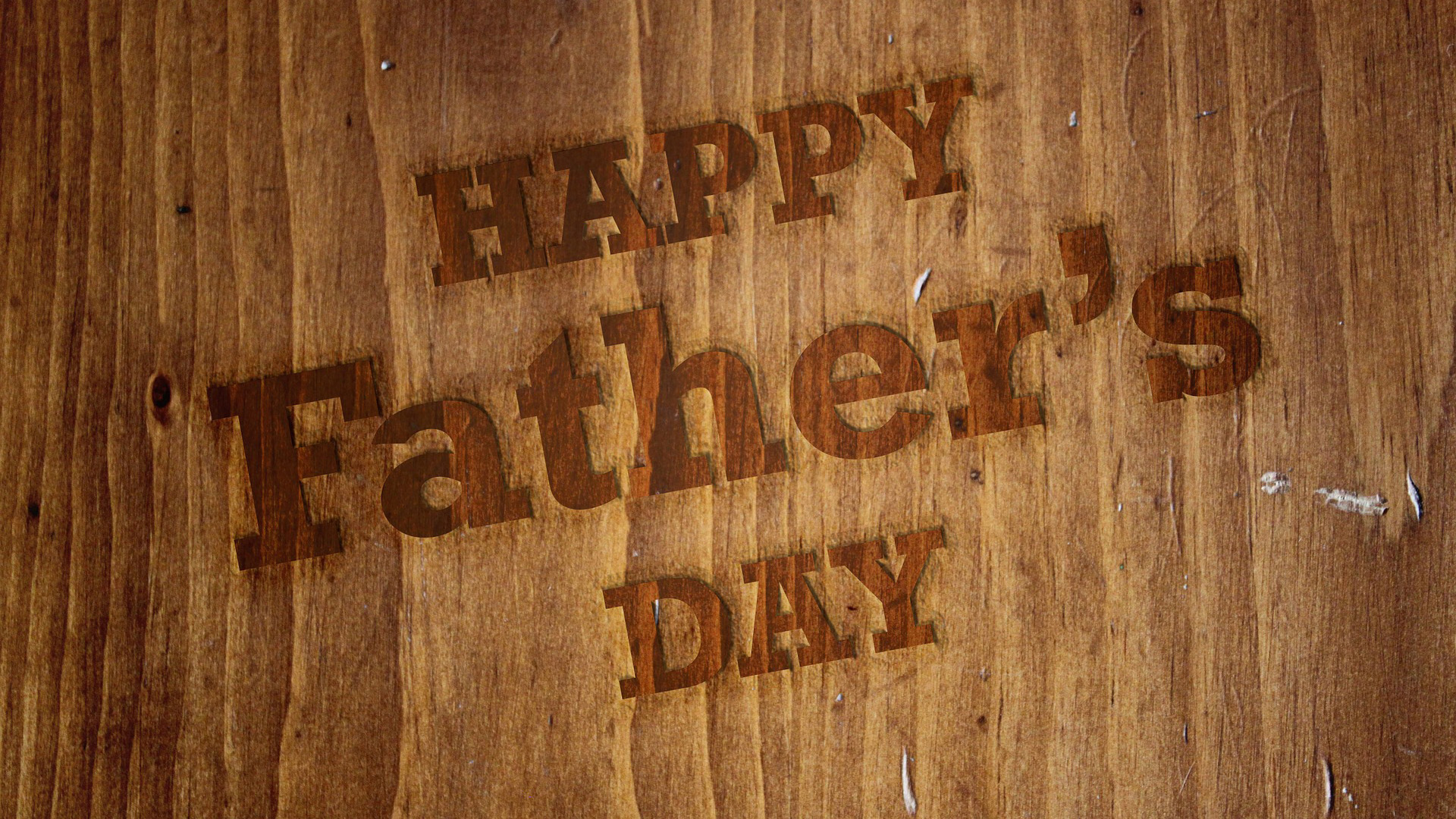 Wooden background with Happy Father's Day embossed in the wood.