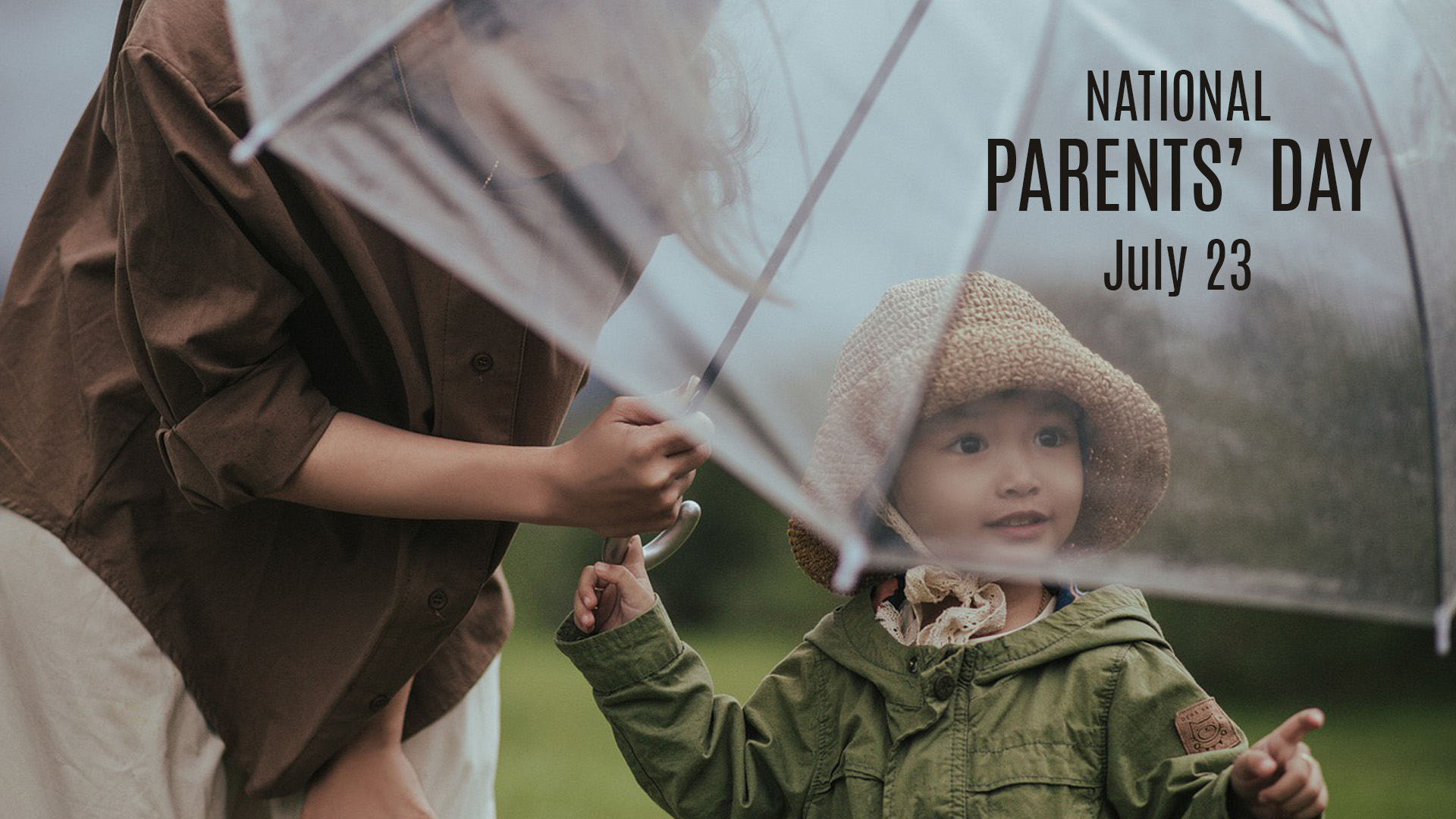 A image of a person bending over holding an umbrella over a child who is in a jacket with a hat. The child is pointing to the right. In the top right side of the image there is text that reads National Parents' Day July 23