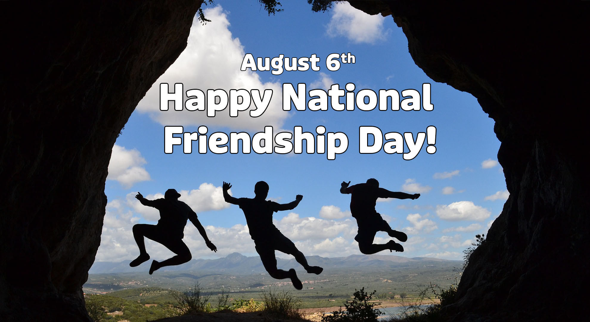 Photo is taken inside a cave looking out to a scene of mountains and hills. There are 3 people jumping and posing in the air. Above them reads August 6th Happy National Friendship Day! In a white sans serif font with a black outline.
