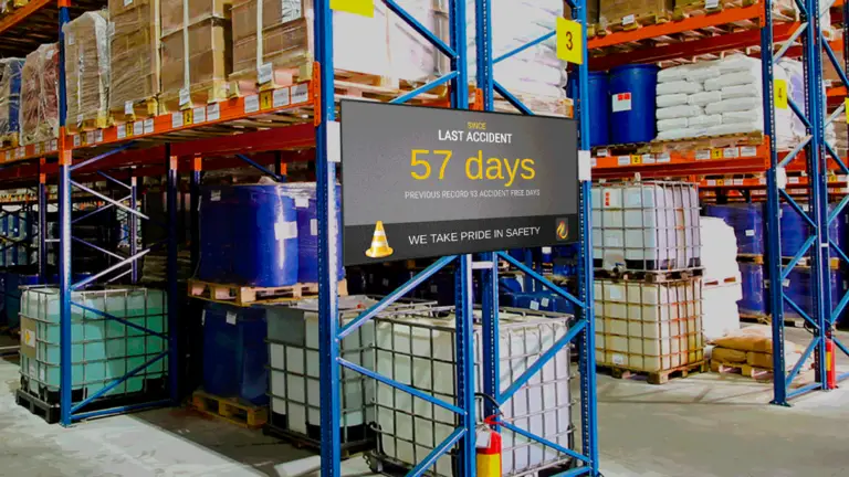 A safety digital signage display in front of manufacturing equipment