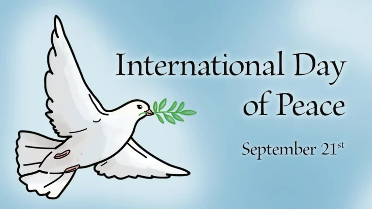 A dusty sky blue background. Right aligned on the right side of the image is the message 'International Day of Peace September 21st' in black serif letters with a faded white drop shadow. Flyin up from the bottom left corner and filling the left side of the image is an illustration of a white dove holding a green leafed plant in its beak. The dove also has a white drop shadow behind it.