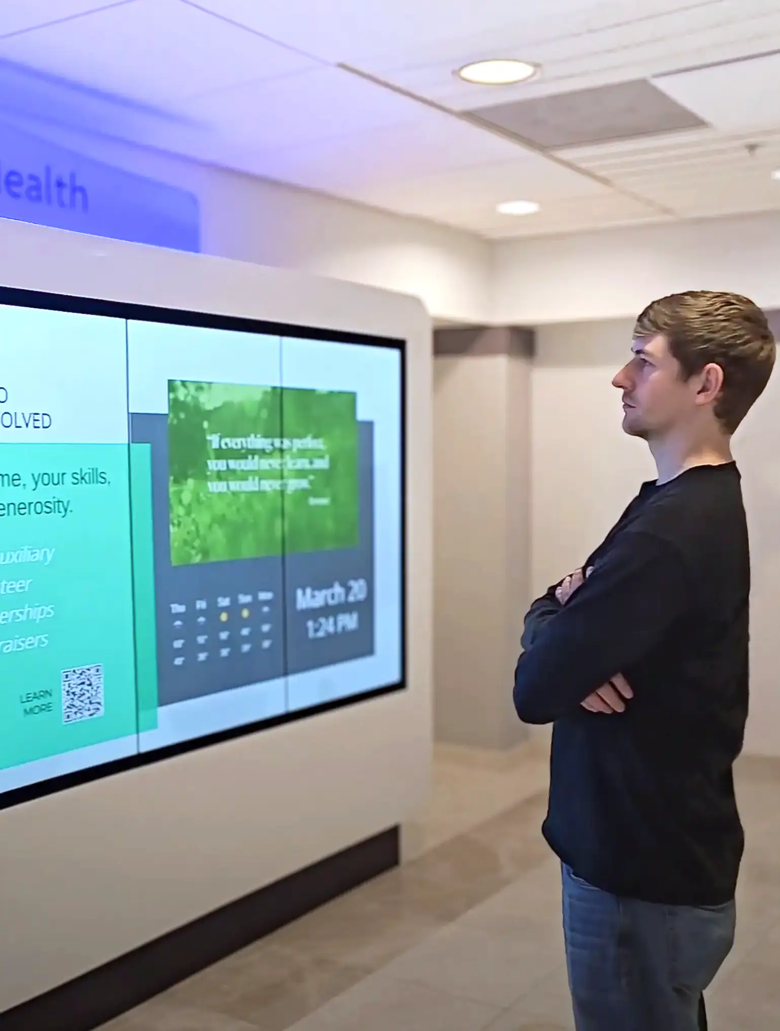 A large white  kiosk with five screens stands in the waiting room of the hospital lobby. Digital Signage content with donor names are scrolling on the screen.