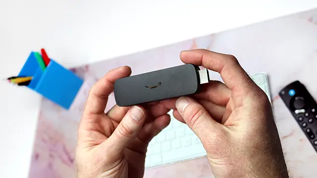 Hands holding an Amazon Signage Stick shows how small it is. Easy to fit behind your screen when running Arreya Digital Signs