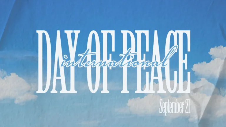 A photo of a blue sky white fluffy, white clouds near the bottom corners fills the graphic. The photo is distressed to look as if it is on old, crinkled and folded paper. Large and in the center is the words ‘DAY OF PEACE’ in condensed, all-caps, white serif letters. Over top and centered is the word ‘international’ in a small, blue, cursive font with a white outline. Below the bottom right corner of the word ‘peace’ is the date September 21 in the same white serif font, but much smaller in size.