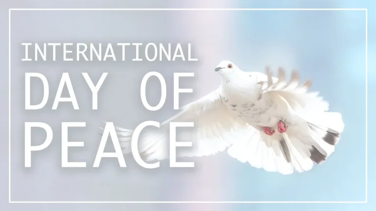 A photo of a flying white dove on the right side of the graphic against a blurred gray, pink, and blue background. A thin white rectangle border is inset around the entire graphic. Left aligned, stacked, and filling the left side are the words ‘International,’ ‘Day of,’ and ‘Peace.’ The words all use the same, semi-bold, white, sans font with a faint gray drop shadow. Each line is the same width, so the heights all vary.