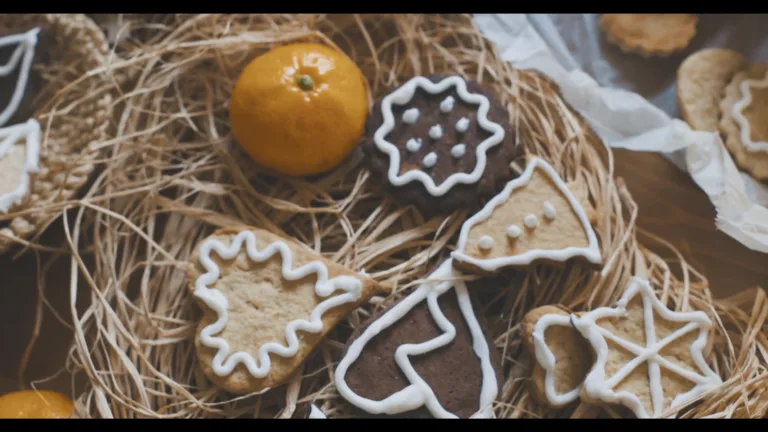 A panning video of chocolate and sugar cookies scattered on top of a wooden table and basket. The cookies are decorated in white frosting.