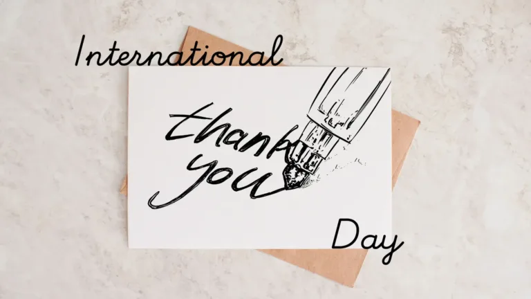 A birds-eye view photo of a stone counter top with a white card overtop a brown paper envelope in the center. The card has a black drawing on it. The drawing is a fountain pen writing out the words thank you. On top of the card, and near the left corner is the word International. Overtop the bottom right corner of the card is the word Day. International and Day use an italic, cursive, black, sans font.