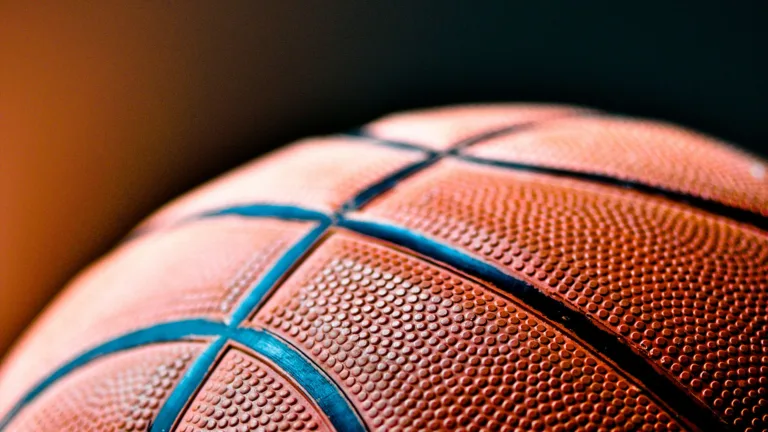 A close up photo of the top of a basketball. The background is an orange to black gradient.