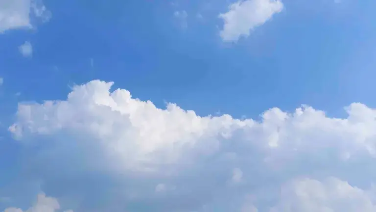 A time lapse video of a fluffy white clouds moving in the sky on a sunny day.