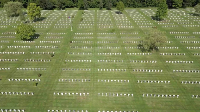 A panning drone video of a graveyard filled with white cross, stone markers.