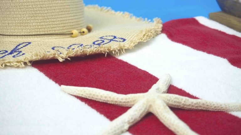 The video slowly pans closer into a red and white striped towel with a dried starfish and straw hat sitting on top of it.