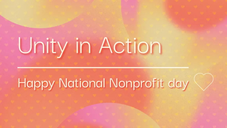 A pink, yellow, and orange gradient background with a small heart shaped patterned overlaid on top of it. Left aligned in the center is a message using thin, white sans letters with a faint red drop shadow. The top line reads, 'Unity in Action' and is largest in size. Then a thin, white horizontal line is below it. Next 'Happy National Nonprofit day' in smaller letters. A very thin white heart outline is next to the last line of text.